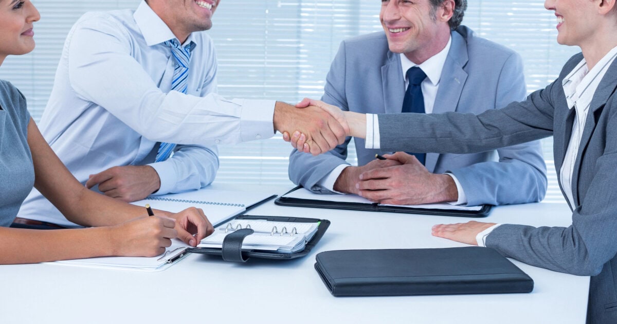 young female job applicant shakes hands with a group of business people; she just might be having an on-campus interview in law school