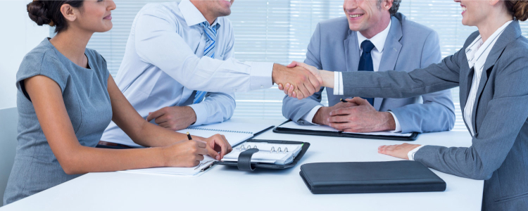 young female job applicant shakes hands with a group of business people; she just might be having an on-campus interview in law school