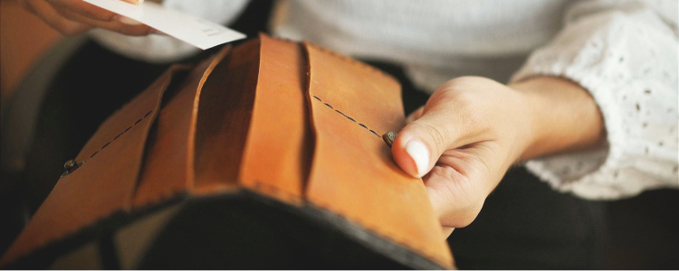 woman opens brown wallet with a long shape but no zipper