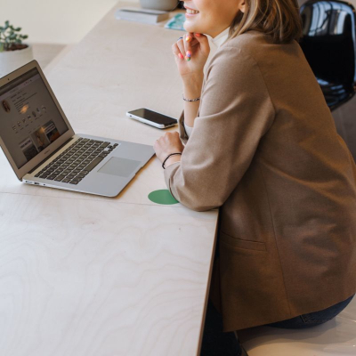 woman smiles wistfully at a laptop; the businesswoman has left corporate life and is happily working on her own time