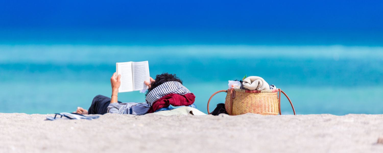 woman relaxes on beach with a book; she just might be a lawyer on a paid sabbatical from her job