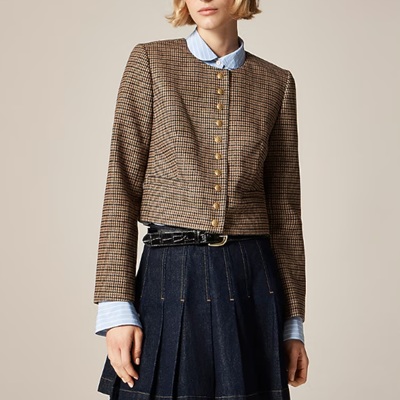 A woman wearing a brown pleated wool jacket with denim skirt