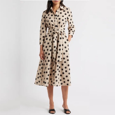 A woman wearing a beige polka dot long sleeve dress