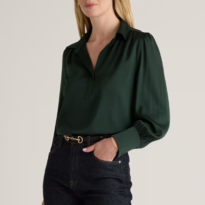 A woman wearing a dark green long sleeve polo top with dark denim pants