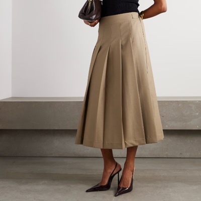 A woman wearing a light brown midi skirt and maroon heels
