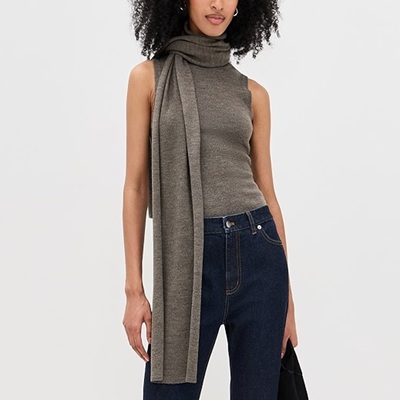 A woman wearing a gray sleeve less top with gray scarf and dark blue denim pants
