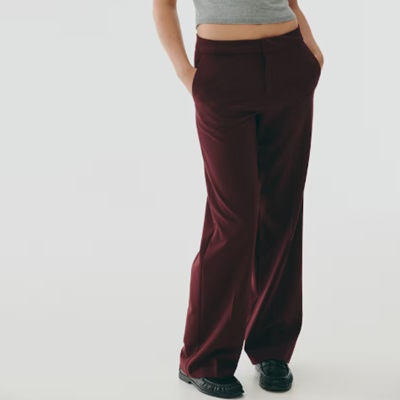 A woman wearing a maroon trouser pants