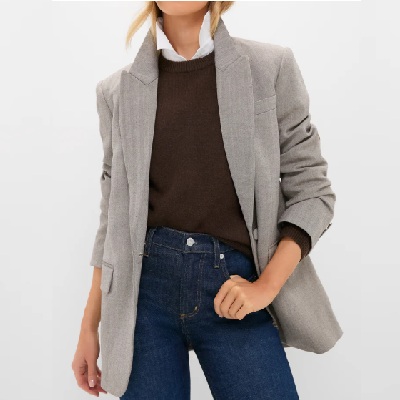 A woman wearing a gray suede blazer and brown long sleeve inner top with pair of denim pants