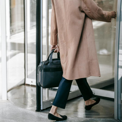 Professional woman wears work outfit and winter coat, she isn't wearing ANY socks with her loafers (gasp)