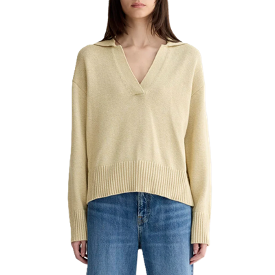 woman wears beige cotton polo sweater and blue jeans
