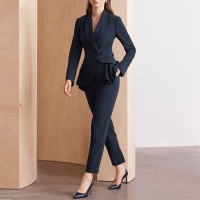 woman wears navy suit with slightly cropped pants nd flounce details