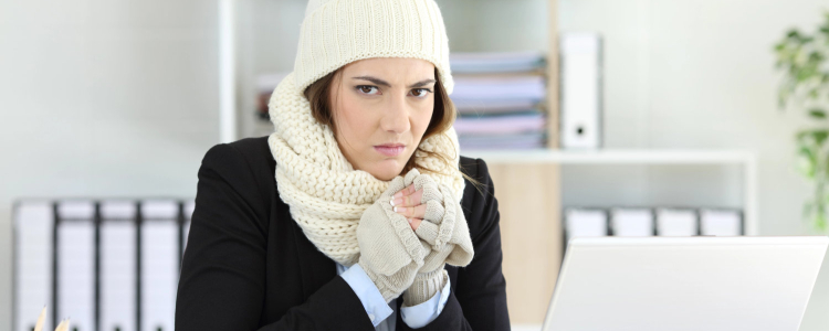 cold businesswoman glares at camera wearing a hat, scarf, and gloves with her blazer