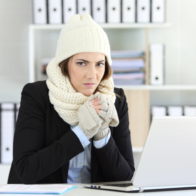 cold businesswoman glares at camera wearing a hat, scarf, and gloves with her blazer