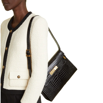 black woman wears white lady jacket with black trim and carries a black structured croc bag