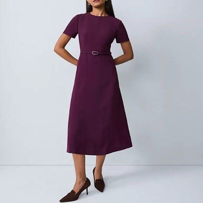 A woman wearing a dark purple midi dress with purple sandals