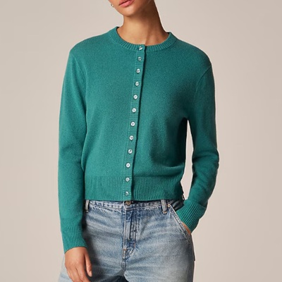 A woman wearing a green cardigan top with denim pants