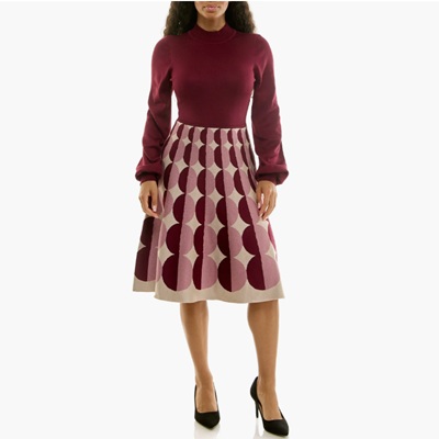 A woman wearing a dress with a burgundy geometric pattern on the skirt and solid burgundy on the top. She is also wearing black pumps.