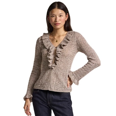A woman wearing a light brown ruffle sweater and dark blue jeans
