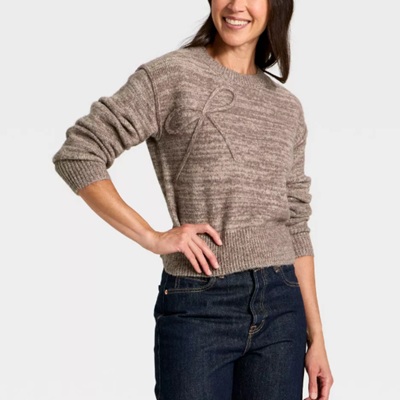 A woman wearing a brown pullover sweater and denim pants