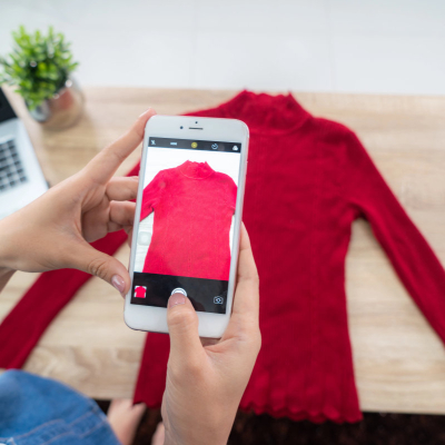 woman photographs red turtleneck sweater in order to sell business clothes online