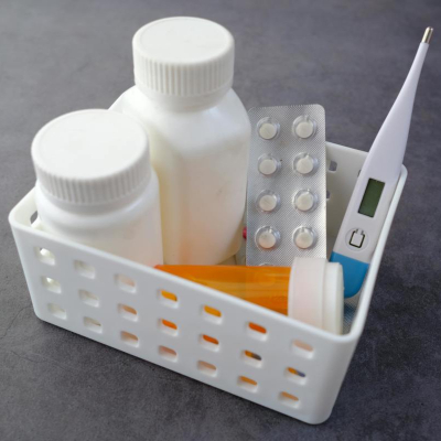 small container filled with pill bottles and packs and a thermometer