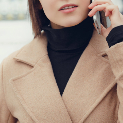 young pretty professional wears a stylish winter coat for women; she is speaking on a cell phone