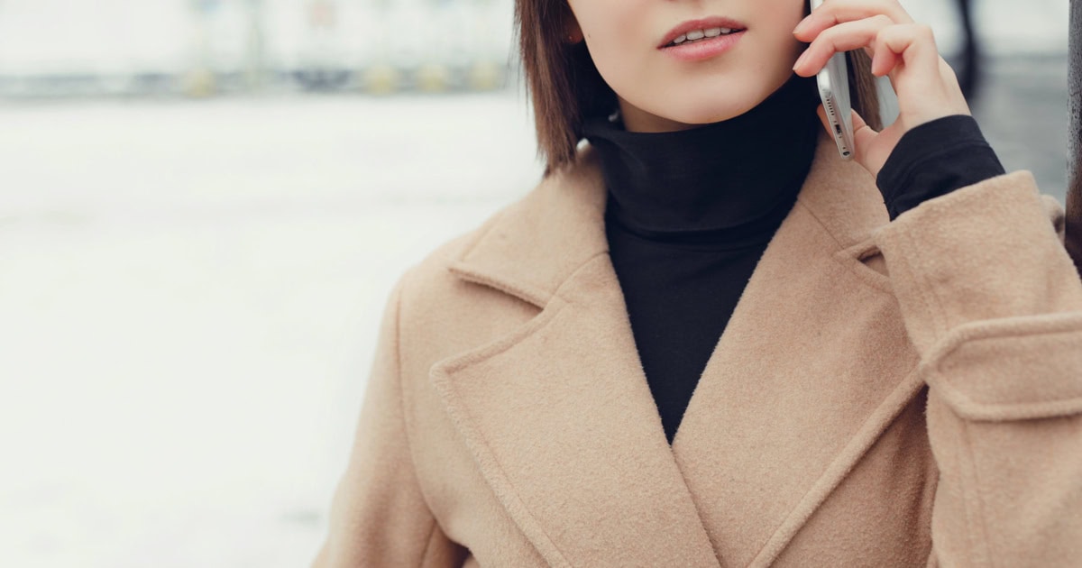 young pretty professional wears a stylish winter coat for women; she is speaking on a cell phone