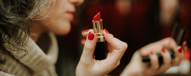 professional woman applies red lipstick using hand mirror