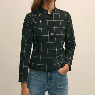 A woman wearing a green pleated crop jacket and denim pants