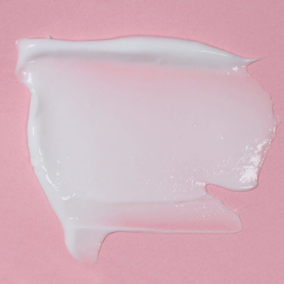 smear of white moisturizer against pink background