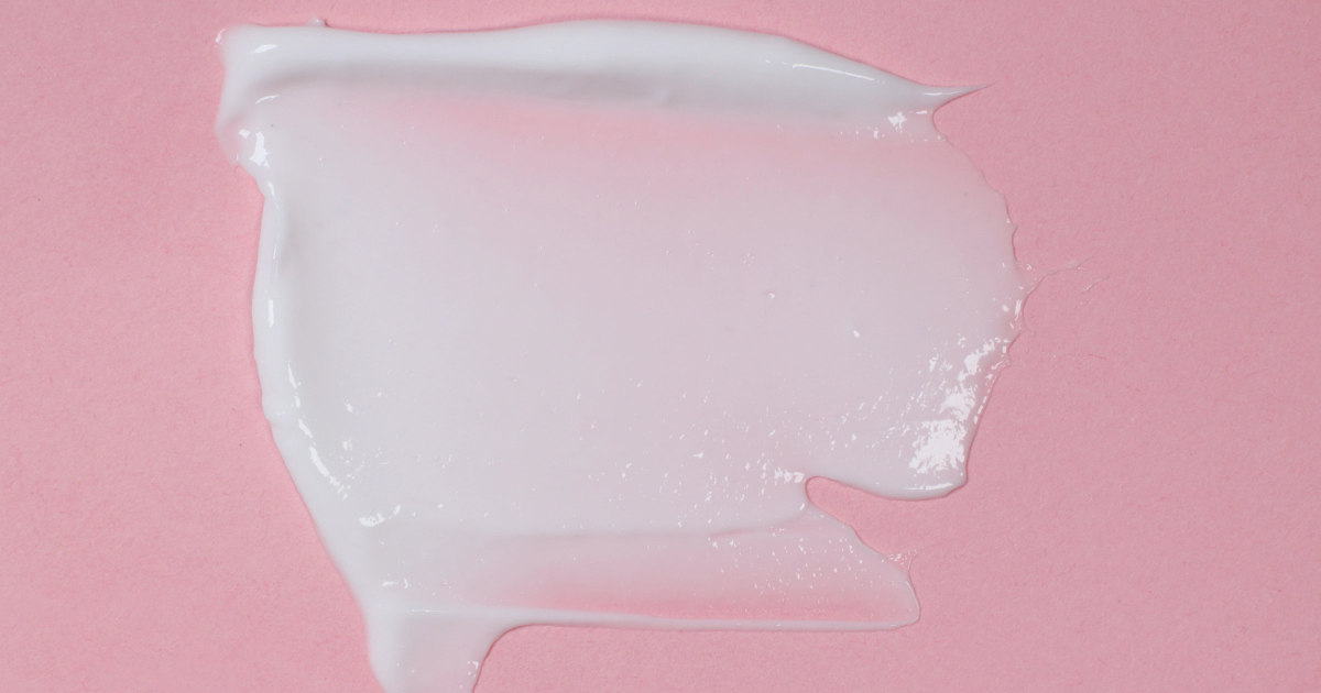 smear of white moisturizer against pink background