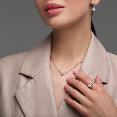 professional woman in beige suit wears a necklace, a ring, and earrings; she's pondering what jewelry is appropriate for the office in 2026