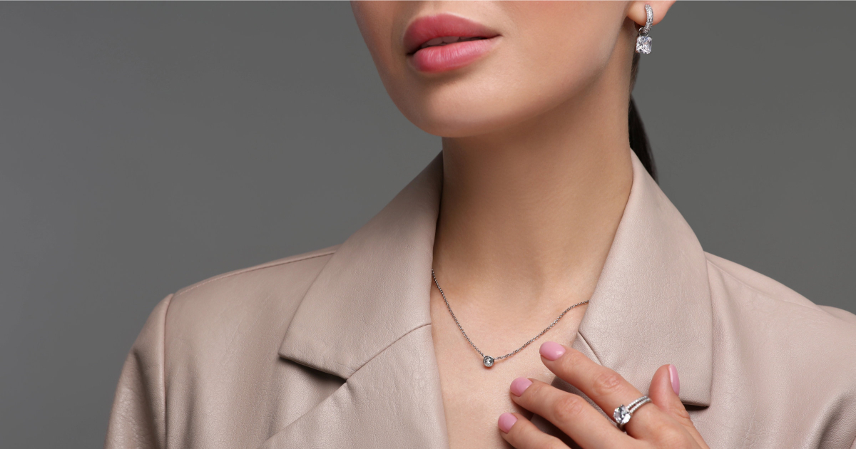 professional woman in beige suit wears a necklace, a ring, and earrings; she's pondering what jewelry is appropriate for the office in 2026