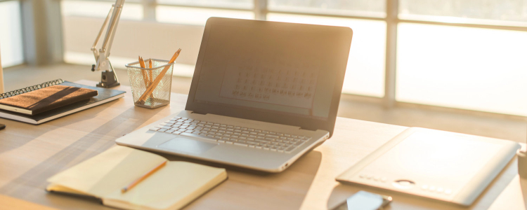 tidy desk with a laptop, pencil cup, notebook, and more arranged perfectly