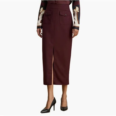 A woman wearing black pumps, a dark brown/maroon midi skirt, and printed blouse