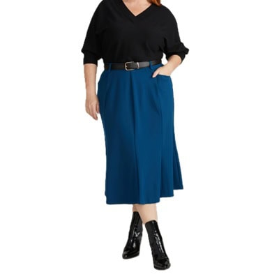 A woman wearing a black top, black belt, black ankle boots, and navy skirt