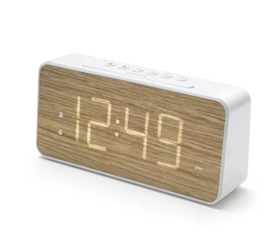 A wood-tone alarm clock with a light-up display and white case