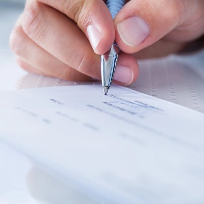 person writes check; they're doing some personal finance tasks in 2026