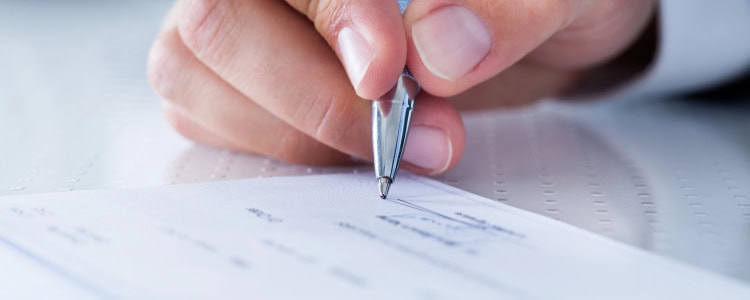 person writes check; they're doing some personal finance tasks in 2026