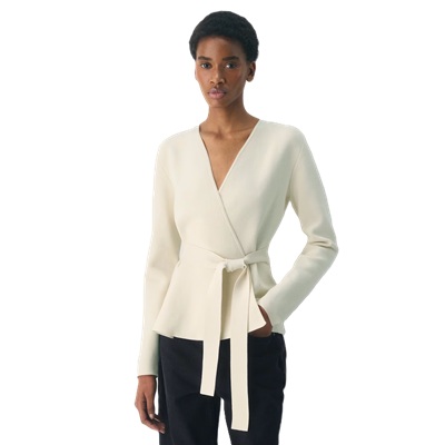 A woman wearing a cream colored cardigan and black pants