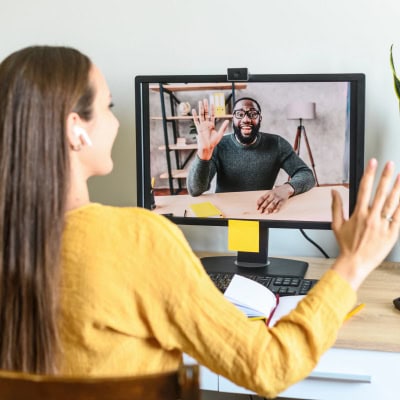 businesswoman waves at a colleague she's meeting with in a Zoom call