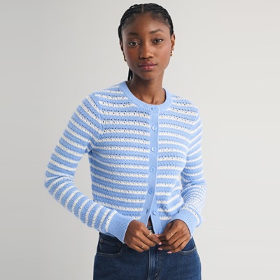 A woman wearing a blue-and-white striped cardigan and dark blue jeans