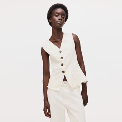 A woman wearing a cream-colored vest and matching pants