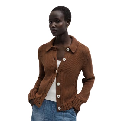 A woman wearing a brown cardigan, white top , and blue jeans