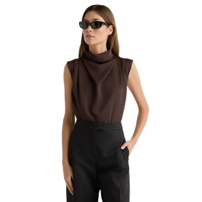 A woman wearing black pants, brown sleeveless top, and black sunglasses