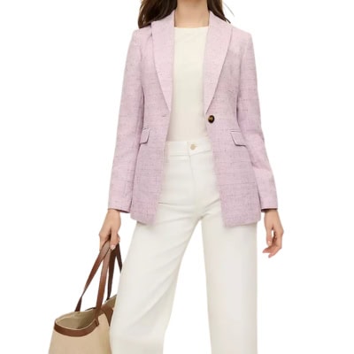 A woman wearing a pink tweed blazer with white pants and white top. She is carrying a tan tote.