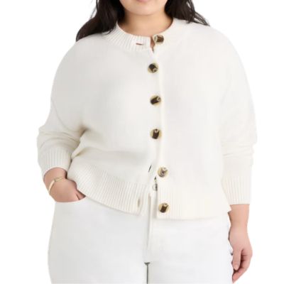 A woman wearing white pants and an ivory cardigan