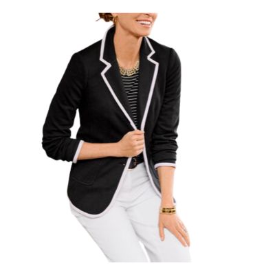 A woman wearing a black blazer with white piping, a black top, and white pants