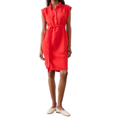A woman wearing a red/orange shirtdress and off-white flats