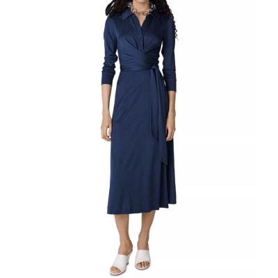 A woman wearing a dark blue midi dress and white slides